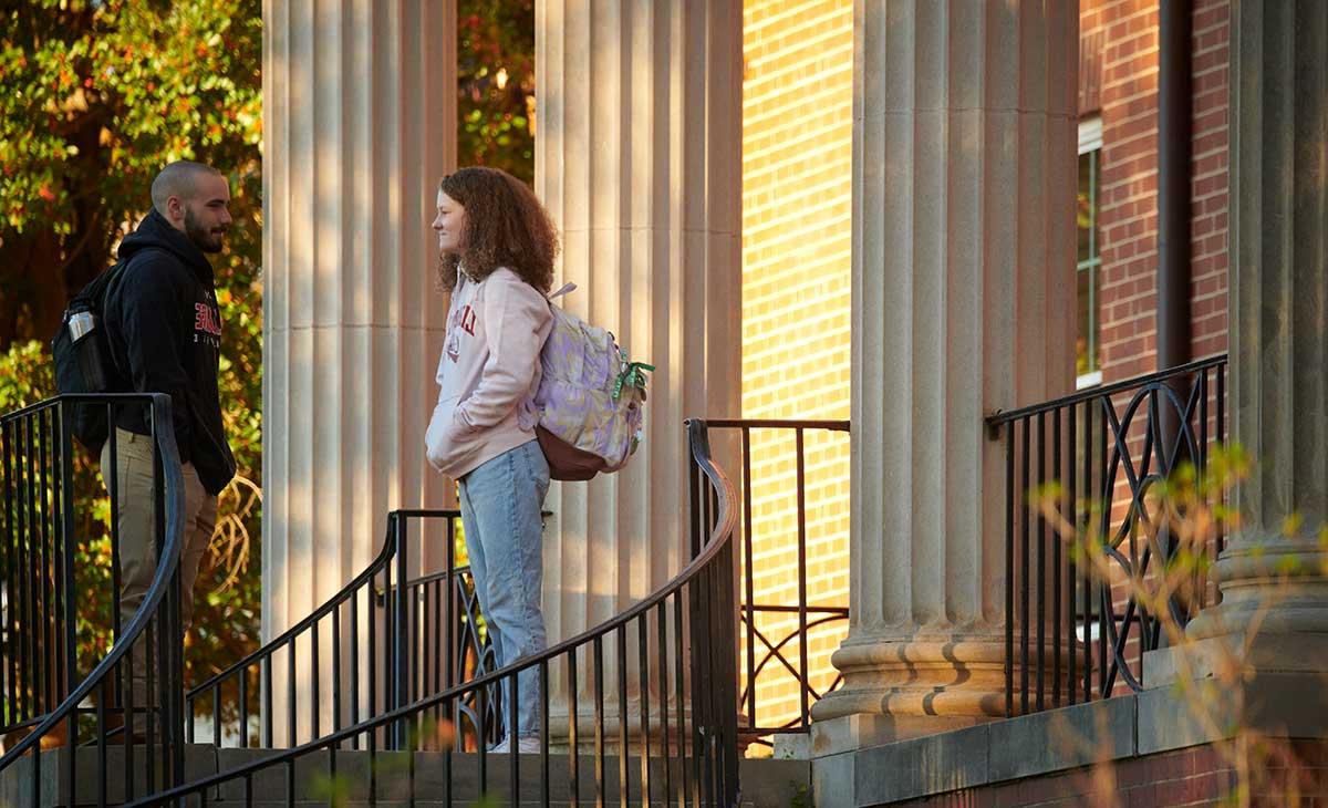 two students talk on a porch