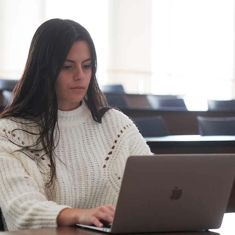 a female student studies on a laptop during a class break